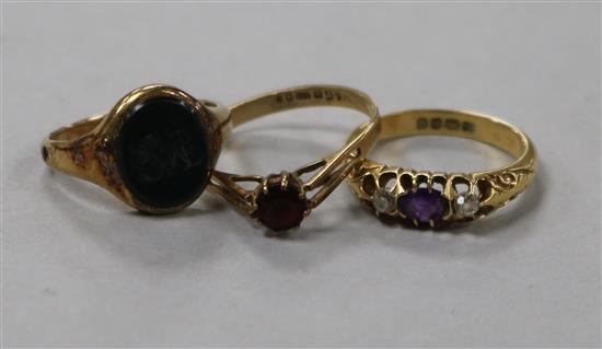 A George V amethyst and diamond three stone ring and two other rings including a bloodstone signet ring with monogram.